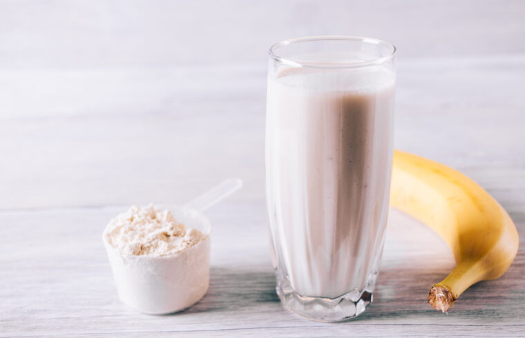 graphicstock protein cocktail in a glass scoop and banana on a white wooden table close up rbeFVBh3vb