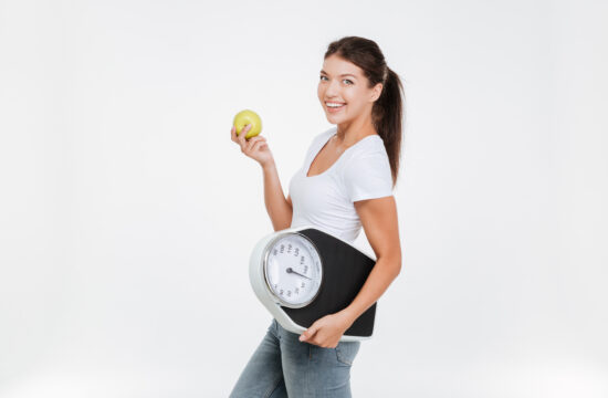 graphicstock woman holding scale and apple for healthy lifestyle and nutrition isolated over white background looking at camera HOxgRXH8ne