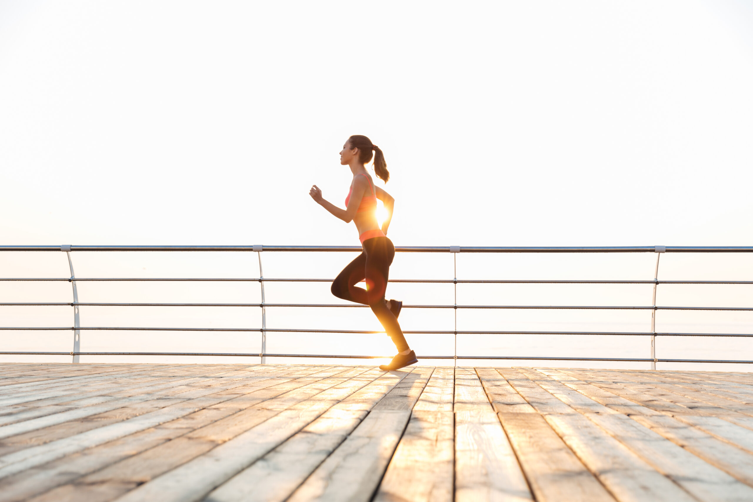 graphicstock cute young sportswoman running on pier in the morning ru4k0ifB2e scaled