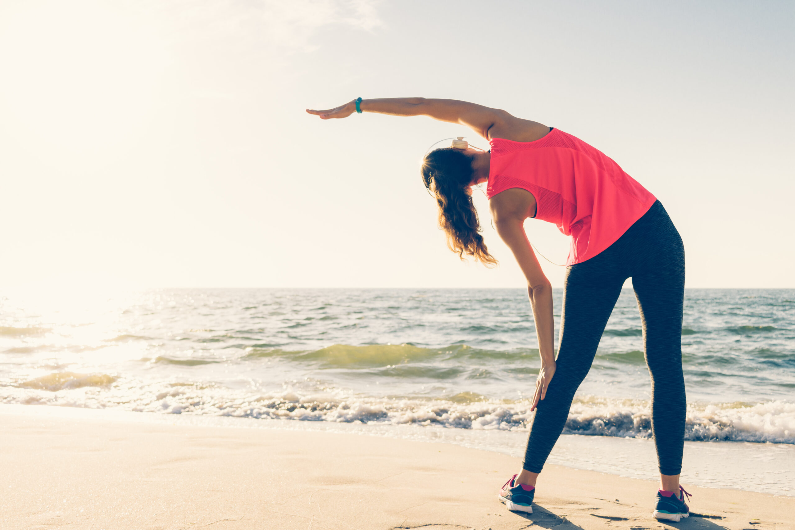 graphicstock athletic girl on the beach in the headphones makes stretching in the morning BZbv6TohPZ scaled